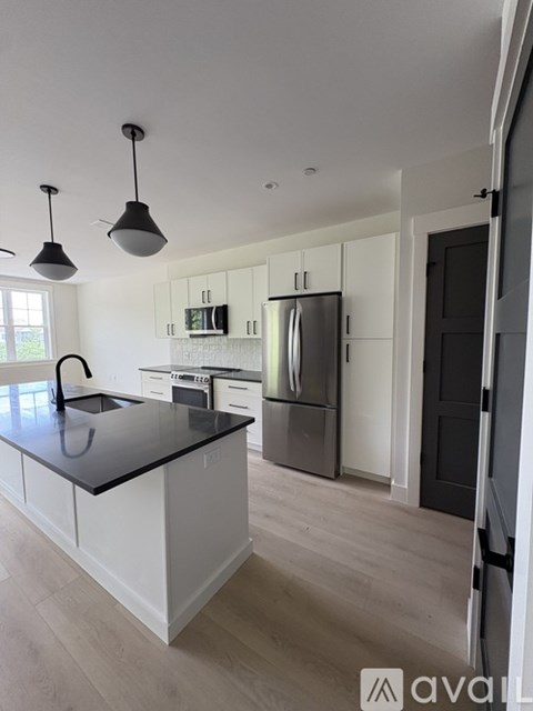 A kitchen with a black countertop and stainless steel appliances.
