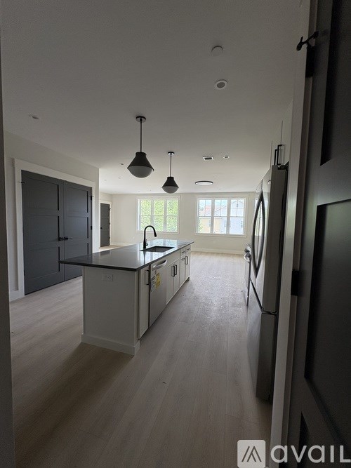 A modern kitchen with a large island and pendant lights.