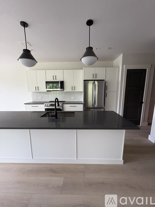 A kitchen with a black countertop and white cabinets.