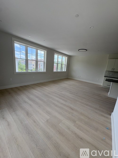 A spacious room with wooden flooring and large windows.
