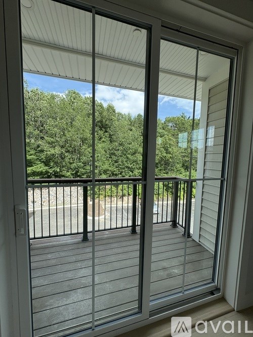A patio door with a view of a parking lot and trees.