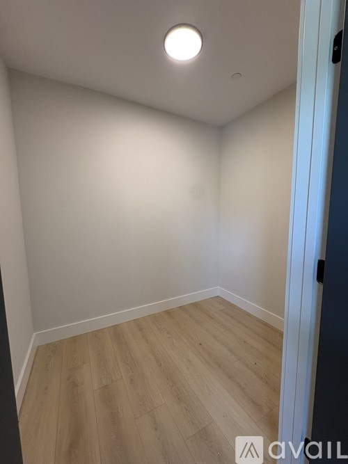 A room with wooden flooring and a white ceiling with a light fixture.