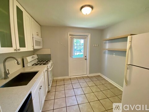A kitchen with white cabinets and a black countertop.