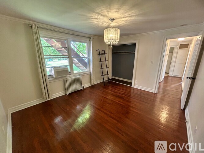 A room with wooden floors and a chandelier hanging from the ceiling.