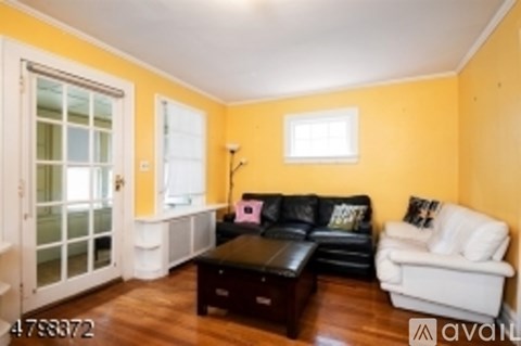 A living room with a black leather couch and a white couch.