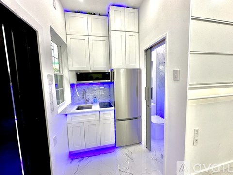 A modern kitchen with white cabinets and a marble floor.