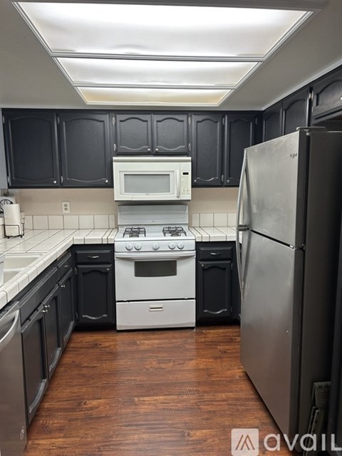 A kitchen with black cabinets and a white stove top oven.
