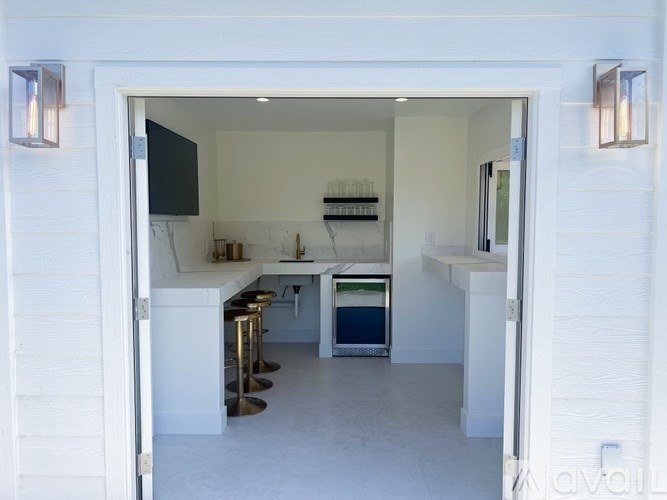 A white kitchen with a bar area and a fridge.