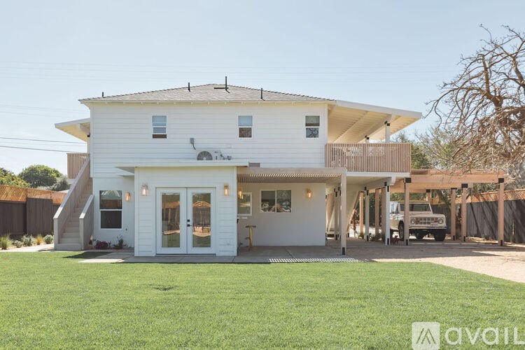 A white house with a brown roof and a covered patio area.