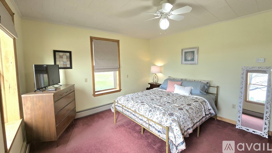 A bedroom with a bed, dresser, and window.