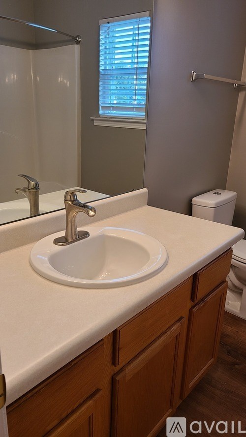 A bathroom with a white sink and wooden cabinets.