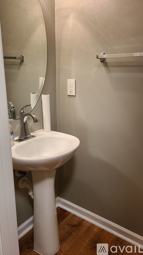 A white pedestal sink in a bathroom with a mirror above it.