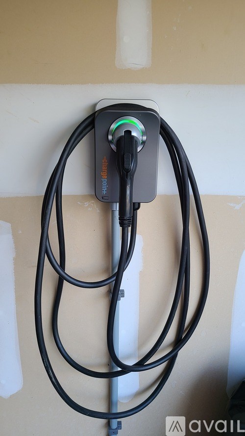 An electric car charging station is plugged into the wall.