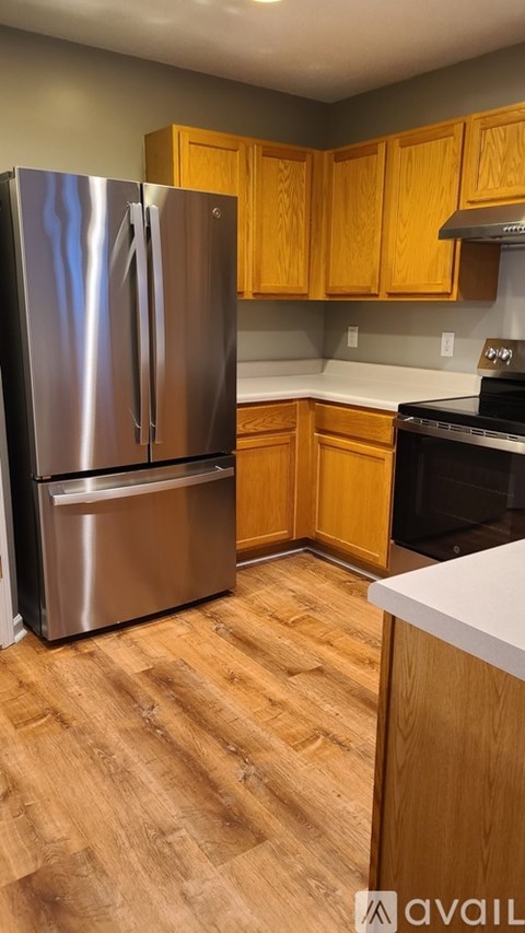 A kitchen with a stainless steel refrigerator and wooden cabinets.
