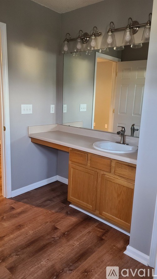 A bathroom with a wooden vanity and a mirror above the sink.