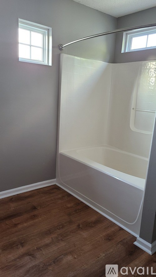 A bathroom with a walk-in shower and wooden flooring.