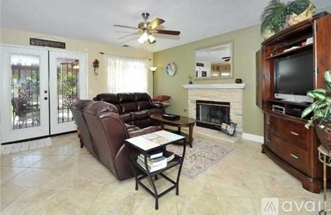 A living room with a brown leather couch and a fireplace.