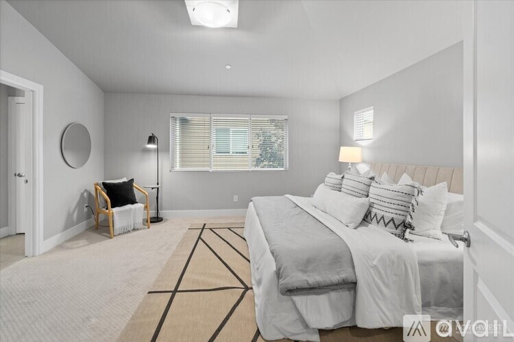 A bedroom with a large bed and a window with blinds.