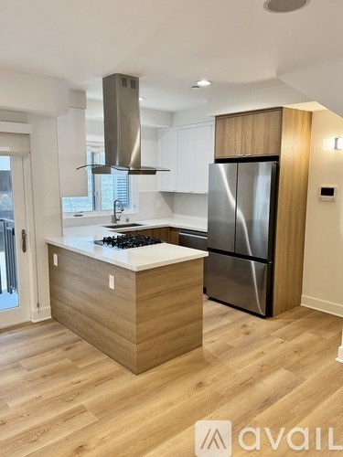 A modern kitchen with wooden floors and a stainless steel refrigerator.