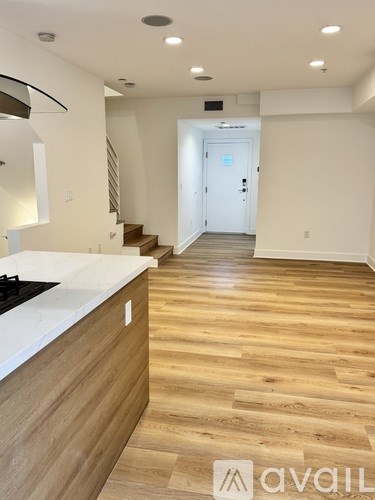 A modern kitchen with wooden floors and a white countertop.