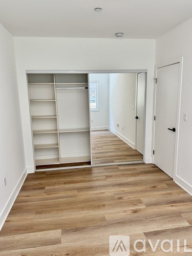 A room with a white wall and a white closet with shelves.