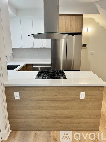 A modern kitchen with a stainless steel refrigerator and a white countertop.