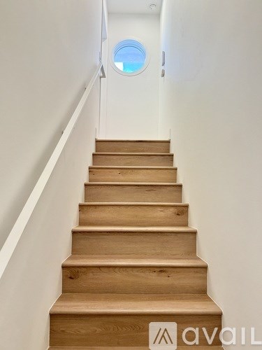 A set of wooden stairs leading up to a round window.