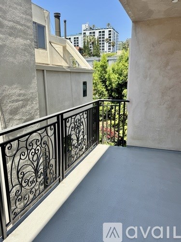 A balcony with a black railing and a view of buildings in the distance.