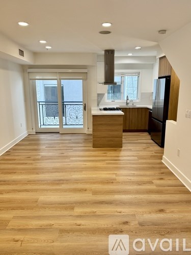 A spacious kitchen with wooden flooring and a large window.