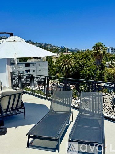 Two chairs and a table are on a balcony with a view of a city.