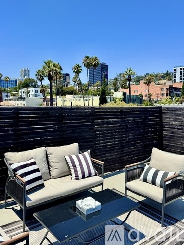 A patio with two couches and a coffee table with a view of the city.