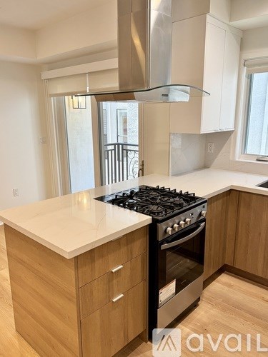 A modern kitchen with a stove top oven and wooden cabinets.