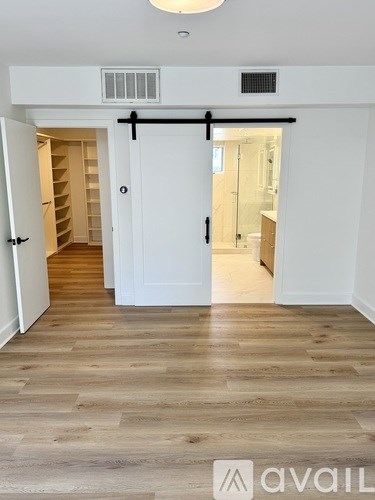 A room with a white door and a wooden floor.