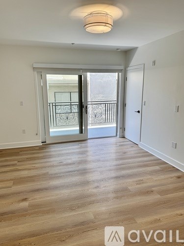 A room with wooden flooring and a balcony with a railing.