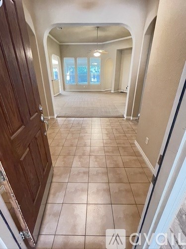 A hallway with a tiled floor and a wooden door.