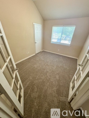 A room with a carpeted floor and a window with blinds.