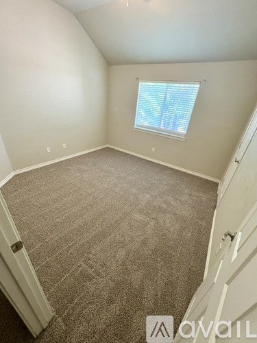 A carpeted room with a window and a door.