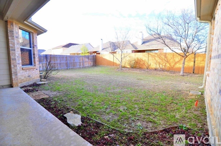 A backyard with a fence and a tree.