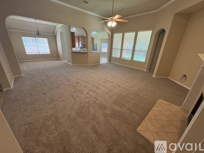 A spacious living room with a carpeted floor and a ceiling fan.