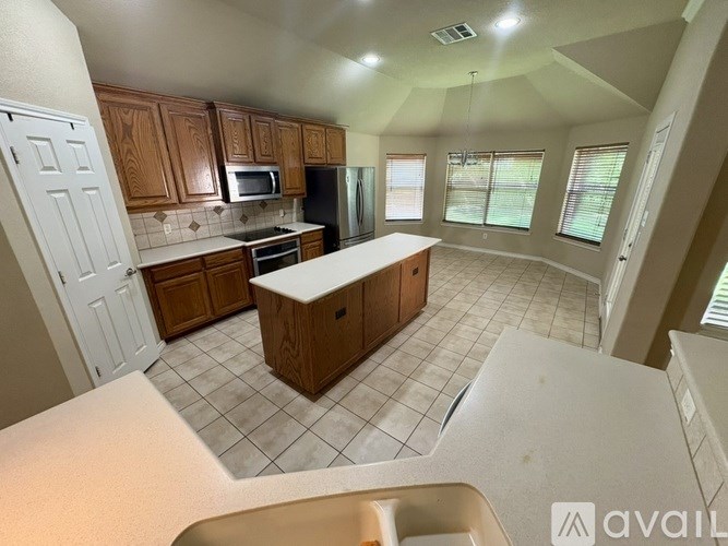 A kitchen with wooden cabinets and a white island.