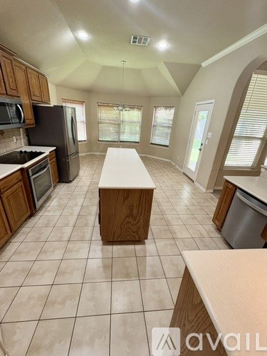 A kitchen with a white tile floor and wooden cabinets.