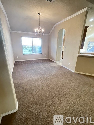 A room with a carpeted floor and a chandelier hanging from the ceiling.