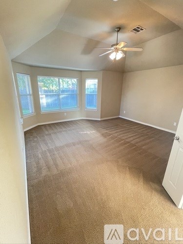 A room with a carpeted floor and a ceiling fan.