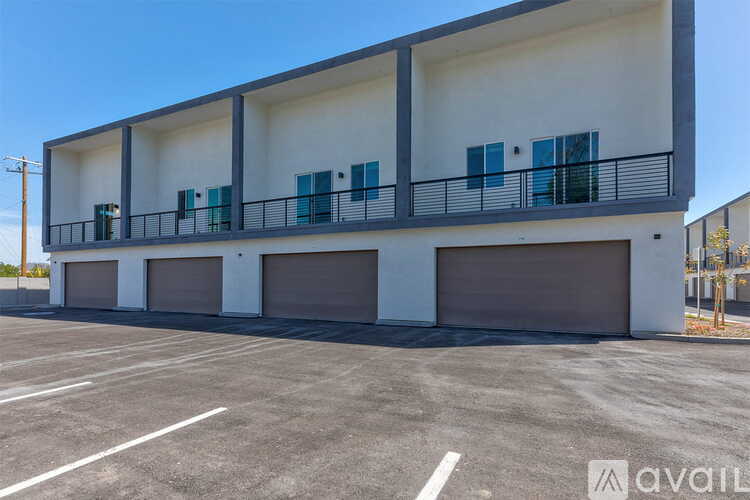A modern two-story building with a balcony and garage doors.
