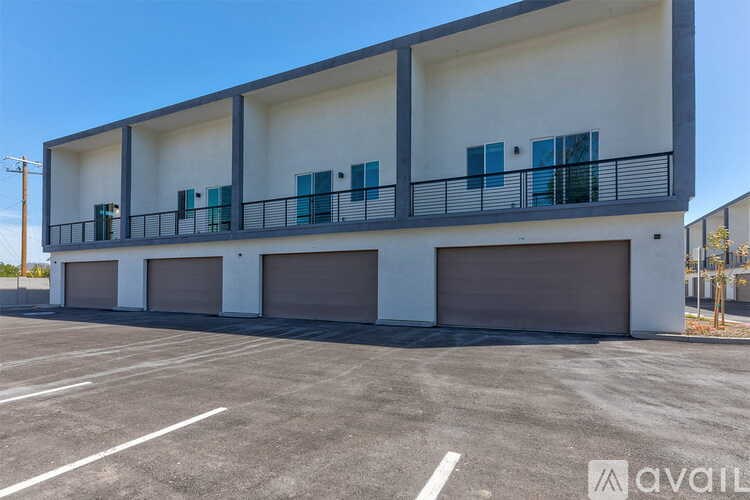 A modern two-story building with a balcony and garage doors.