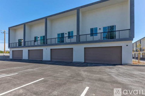 A modern two-story building with a balcony and garage doors.