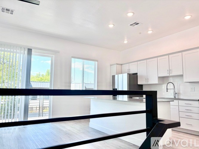 A modern kitchen with white cabinets and a black railing.