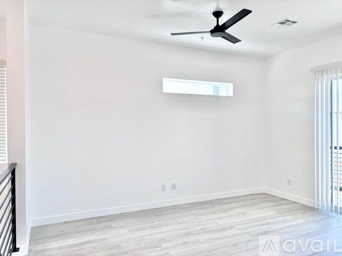 A room with a ceiling fan and a window with blinds.