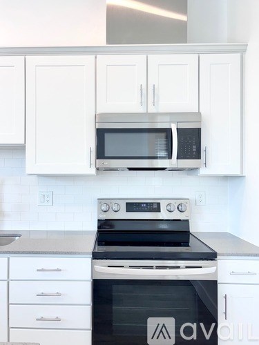 A white kitchen with a black stove top oven and a black microwave above it.