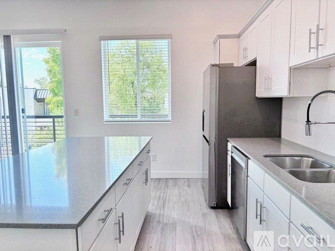 A kitchen with a refrigerator, sink, and cabinets.